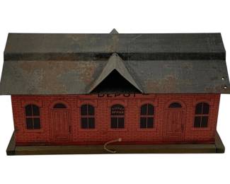 1000 - Metal Train Depot 7.5"x13"x7" (Description): Metal train depot building with lithographed brick exterior design. Features a ticket office window and multiple arched windows. Measures 7 1/2 inches by 13 inches by 7 inches.