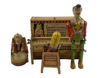 857 - Unique Arts Li'l Abner Dogpatch Band Tin Toy (Description): Unique Arts tin lithograph toy featuring the Li'l Abner Dogpatch Band. This vintage wind-up toy depicts a colorful musical scene with a piano marked "Turnip Time by Li'l Abner," accompanied by band member figures including a drummer and pianist. The toy showcases vibrant lithographed details in red, yellow, green, and cream tones typical of mid-century tin toys. Measures 7 1/2" x 10" x 6".