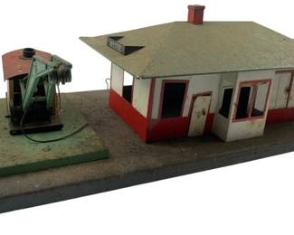 216 - Vtg American Flyer Model Train Accessories (Description): Vintage model train accessories from the American Flyer line. This set features a station building and an accompanying mechanical accessory piece, both mounted on a shared base. The pieces show authentic vintage patina consistent with their age. Measures 6" x 19" x 8".