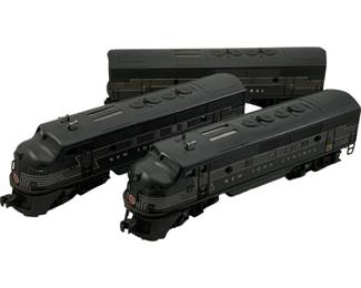 1202 - 3pc Lionel O Scale New York Central Trains (Description): Set of three Lionel O Scale model trains in New York Central livery. The collection includes two diesel locomotive engines and one passenger car, all finished in the classic dark gray and black New York Central color scheme with silver striping details. Each piece features the New York Central logo on the nose. Measures 8 inches by 4 inches by 3 inches.