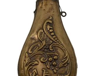 973 - Brass Powder Horn 7.5"x3.5"x1.25" (Description): Brass powder horn featuring decorative embossed scrollwork and floral motifs. The flask includes a spring-loaded dispensing mechanism at the top with a small ring attachment. Measures 7.5 inches by 3.5 inches by 1.25 inches.