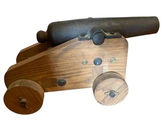 31 - Wood & Cast Iron Cannon 11.5"x23"x11.5" (Description): Decorative wood and cast iron cannon model featuring a black cast iron barrel mounted on an oak carriage with wooden wheels. The carriage is assembled with metal hardware including bolts and wing nuts, allowing for adjustment of the barrel angle. A handsome nautical or military display piece. Measures 11 1/2" x 23" x 11.5".