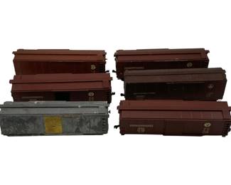 922 - Large Lot HO Scale Train Cars 2.5"x7"x2" (Description): Large lot of HO scale train cars measuring 2.5 inches by 7 inches by 2 inches each. This collection includes seven boxcars featuring various railroad liveries including Pennsylvania Railroad and Baltimore & Ohio. The cars are predominantly finished in maroon/tuscan red with one car showing weathered silver/gray finish with yellow markings. The lot displays varying degrees of wear consistent with use and age.