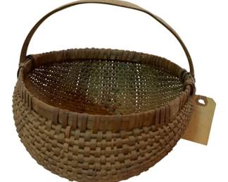 78 - Primitive Polychrome Basket w/Handle 8"x8"x8" (Description): Primitive polychrome basket with handle. This handwoven wicker basket features a rounded form with tightly woven splint construction. The bentwood swing handle is attached at the rim. The basket displays a warm natural patina with subtle color variations consistent with age and use. Measures 8" x 8" x 8".