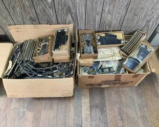 334 - Märklin Train Tracks Box Lot (Description): A box lot of vintage Marklin model train tracks and components. The collection includes various track sections, switches, and accessories, some in original cardboard boxes with period packaging. The lot spans two large boxes containing numerous pieces for model railroad enthusiasts. Measures approximately 10 inches.