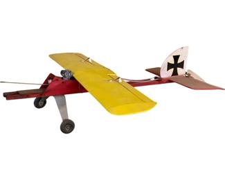 1086 - Gas Powered Model Plane Damaged 17"x40"x48" (Description): Gas powered model airplane in damaged condition. This vintage-style model features a red fuselage with yellow fabric-covered wings and a tail section decorated with a black Iron Cross insignia, reminiscent of WWI German aircraft. The plane is equipped with a small gas engine mounted at the front and sits on a tricycle landing gear configuration. Measures 17"x40"x48".