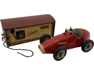 1212 - Schuco Tin Racer & Garage Set (Description): Two-piece lot featuring a Schuco racer and garage. The red tin litho race car features a detailed open cockpit with driver figure, chrome exhaust pipes, and rubber tires. The accompanying tin garage displays a brick pattern design with the Schuco logo and features a rotary dial mechanism on the front. Measures 2.5" x 5.5" x 3.5". Used as is electric/electronic/mechanical item. No guarantee all components, untested.