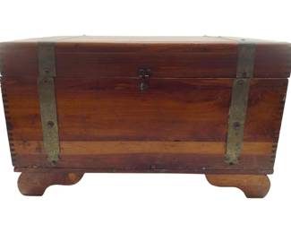 90 - Vtg Small Cedar Wood Chest w/ Metal 9"x15"x9" (Description): Vintage small cedar wood chest featuring strap hardware and a front latch closure. The chest displays dovetail joinery at the corners and rests on shaped bracket feet. A warm reddish-brown finish highlights the natural cedar wood grain. Measures 9 inches high by 15 inches wide by 9 inches deep.