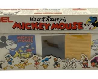 831 - Lionel Mickey Mouse Box Car O Scale in Box (Description): Lionel Walt Disney's Mickey Mouse Express box car in O scale, complete with original box. This 1977 Walt Disney Productions licensed train car features colorful Disney character graphics on the packaging including Mickey Mouse, Donald Duck, Minnie Mouse, Pinocchio, and other classic Disney characters. The set includes a white box car with Mickey Mouse artwork and a yellow freight car. Original packaging shows age-appropriate wear.
