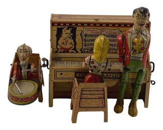 858 - Unique Arts Li'l Abner Dogpatch Band Tin Toy (Description): Unique Arts tin lithograph toy featuring the Li'l Abner Dogpatch Band. This colorful wind-up toy depicts characters from the classic comic strip, including a piano player at an upright piano decorated with "Turnip Time by Li'l Abner" sheet music and a pig illustration, accompanied by a drummer figure with snare drum. The figures are dressed in characteristic hillbilly attire with polka dots and colorful clothing. Includes a small
