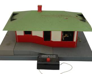 516 - American Flyer O Scale Talking Station (Description): American Flyer O Scale house talking station with control box. The station features a classic design with a green roof, red chimney, and red and white exterior. Includes original wired control box labeled "American Flyer Talking Station." Measures 7 inches by 12 inches by 8 inches.