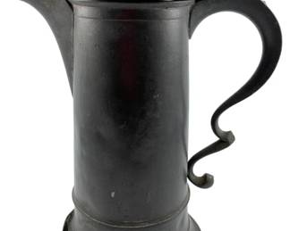 122 - Antique Pewter Flagon 12"x9"x5.5" (Description): Antique pewter flagon in good condition with no damage. This handsome vessel features a tall cylindrical body with a flared base, hinged domed lid, and an elegant scrolled handle with decorative thumb piece. The pewter has developed a rich dark patina consistent with age. The flagon measures 12 inches by 9 inches by 5.5 inches.