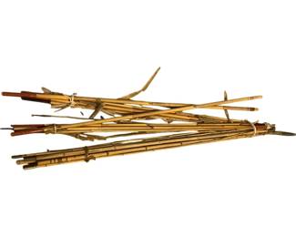 1142 - Lot Bamboo Poles 54" (Description): A collection of natural bamboo poles in varying thicknesses and conditions. Some poles retain their original nodes and natural coloring, while others show signs of age and weathering. Several poles are bundled together with twine or natural fiber ties. The lot includes both straight poles and some with natural branching. Measures 54 inches in length.