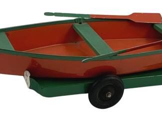 894 - Kingsbury Metal Boat w/ Trailer 3"x11"x5" (Description): Kingsbury metal toy boat with trailer. The boat features a red and green painted finish with two cross seats and a pair of oars. The matching green trailer has rubber wheels. Measures 3 inches by 11 inches by 5 inches.