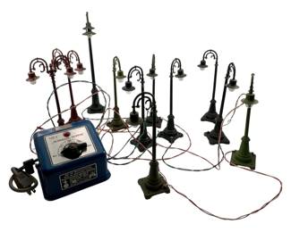 28 - Marklin Super Conductor w/ Railroad Lights (Description): A vintage Marklin Super conductor transformer with a collection of model railroad street lights. The blue metal transformer is marked 110V and features a dial control. The lot includes approximately eleven miniature lamp posts in various styles and finishes, including single and multi-light designs in painted metal. The lights retain their original wiring for connection to the transformer.