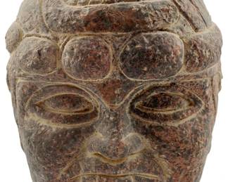 100 - Vintage Olmec-Style Head Sculpture 7"x6"x5" (Description): Vintage Olmec-style head sculpture carved from mottled reddish-brown and black stone. The piece features characteristic Mesoamerican styling with incised linear details on the headdress, prominent almond-shaped eyes, broad nose, and full lips. The surface shows natural weathering and patina consistent with age. Measures 7" x 6" x 5".