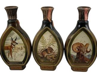 1026 - 3pc. Lot Jim Beam Bottles 11" (Description): A collection of three Jim Beam's Choice decorative whiskey decanters featuring wildlife artwork. Each bottle displays a different animal scene within an arched frame: a pronghorn antelope, a chipmunk with ferns, and a bighorn ram. Each bottle measures 11 inches in height.