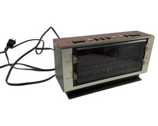 730 - JC Penney Vtg AM/FM Clock Radio (Description): Vintage JC Penney AM/FM dual alarm clock radio with wood grain accents and analog tuning dial. Features separate alarm controls and sleep/snooze functions. Measures 4.5 inches tall by 8.5 inches wide by 2.5 inches deep. Used as is electric/electronic/mechanical item. No guarantee all components, untested.