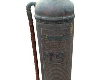 401 - Vtg First Aid Metal Fire Extinguisher 24" (Description): Vintage First Aid metal fire extinguisher. This antique firefighting equipment features embossed text and original hardware. Measures 24 inches tall.
