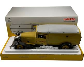 1198 - Marklin Metal Wind-up Delivery Truck w/ Box (Description): Marklin Metal wind-up delivery truck with original box. This vintage die-cast model features a distinctive olive green and gray color scheme with "Marklin" branding on the cab door. The truck includes detailed elements such as opening panels, rubbetires, and a covered cargo area. Presented in its original yellow Marklin Metall packaging with styrofoam insert and illustration of the model on the box. Limited edition, numbered