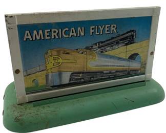 295 - AC Gilbert Co. American Flyer Billboard Stand (Description): AC Gilbert Co. American Flyer billboard stand featuring a colorful lithographed train scene depicting Santa Fe locomotives. The sign is mounted on a mint green painted metal base with visible age-appropriate wear. Measures 5" x 7" x 4". Used as is electric/electronic/mechanical item. No guarantee all components, untested.