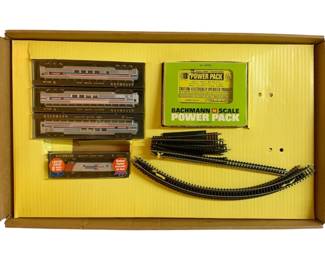 1069 - Bachmann N Scale Train Set w/ Box (Description): Bachmann N Scale train set with original box. The set includes multiple train cars in Amtrak livery, a Bachmann N Scale Power Pack, track sections, and additional accessories. All components are housed in the original packaging.