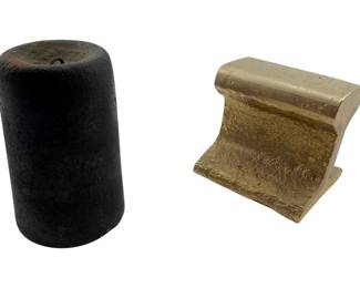 110 - Group of 2 Weights 3.5" (Description): Group of two weights measuring 3.5 inches. The lot includes a cylindrical cast iron weight with a dark patina and a gold-painted railroad rail section paperweight, both suitable for use as desk accessories or decorative objects.