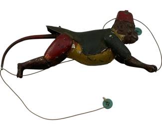 1105 - Antique Tin Litho Monkey Toy 9.5"x2.75" (Description): Antique tin lithograph monkey toy featuring a painted figure wearing a red fez hat, green jacket, yellow vest, and red pants. The articulated toy includes a wire mechanism with button attachments that likely allowed the monkey to perform climbing or acrobatic movements when operated. Shows charming age-related wear consistent with vintage playthings. Measures 9.5" x 2.75".