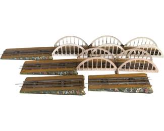 1098 - Tin Litho O Scale Train Bridge Sections (Description): Collection of tin lithograph O scale train bridge sections. The lot includes multiple arched bridge spans with decorative white-painted railings and coordinating track bed sections featuring painted scenic details along the sides. These vintage model railroad accessories would complement an O gauge train layout.