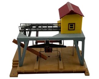 1021 - American Flyer Sawmill 10"x11"x6.5" (Description): American Flyer Sawmill model train accessory. This operating sawmill features an elevated platform with railings, a yellow operator's house with red roof, and a sawing mechanism below. Measures 10 inches by 11 inches by 6.5 inches.