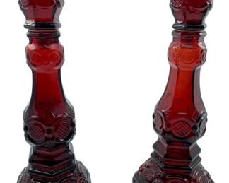 96 - Vtg Avon 1876 Cape Cod Ruby Red Candlesticks (Description): Vintage Avon 1876 Cape Cod ruby red glass candlesticks. This elegant pair features the classic Cape Cod pattern with its distinctive pressed glass design. Each candlestick measures 8.5 inches tall.