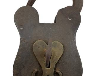 179 - Antique Iron Padlock w/Key 5"x3" (Description): Antique iron padlock with key. This substantial lock features a shield-shaped body constructed of heavy iron with a curved shackle. The front displays a decorative brass escutcheon plate with a heart-shaped or butterfly design surrounding the keyhole, where the original iron key remains inserted. The padlock exhibits an aged patina consistent with its antique age. Measures 5" x 3".