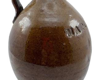124 - Markham, VA Stoneware Jug 8"x5"x5" (Description): A very old stoneware jug with impressed lettering reading "MARKHAM VA" across the shoulder. The jug features a rich brown alkaline glaze with variations in tone and a traditional ovoid form with a pinched pouring spout. This piece represents early Virginia stoneware pottery. Measures 8" x 5" x 5".
