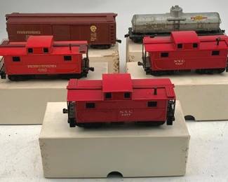 916 - 5pc Lot Lionel HO Scale Trains w/ Boxes (Description): A collection of five Lionel HO scale model trains with original boxes. The lot includes three red N.Y.C. cabooses, one Pennsylvania boxcar in brown, and one silver tank car. Each piece measures approximately 2.5" x 9".