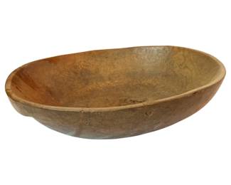 82 - Large Antique Wooden Dough Bowl 7"x25"x22" (Description): Large antique wooden dough bowl with an elongated oval form, hand-hewn from a single piece of wood. The bowl displays a warm, aged patina with natural variations in the wood grain, showing years of use and character. Measures 7 inches tall by 25 inches long by 22 inches wide.