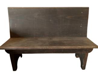 165 - Wooden Church Pew 34"x48"x18" (Description): A rustic wooden church pew with a simple, utilitarian design. The bench features a solid plank seat and straight back panel supported by shaped cutout legs. The piece is finished in a dark stain that has developed a beautiful patina with age, showing authentic wear consistent with years of use. Measures 34 inches high by 48 inches wide by 18 inches deep.