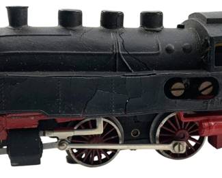 272 - Marklin Locomotive 2"x2"x7" (Description): Marklin locomotive in black with red accents and silver wheels. This vintage model train features a classic steam engine design with three smokestacks, a detailed cab with windows, and spoked driving wheels. The body shows aged crazing to the painted finish consistent with its age. Measures 2"x2"x7".