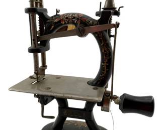 11 - F&W Mfg Co. Midget Hand Crank Sewing Machine (Description): Vintage Midget sewing machine by F&W Mfg Co., dated 1995. This charming hand-crank tabletop sewing machine features a black cast iron body with decorative hand-painted floral and foliate designs in gold, red, and yellow. The machine has a rounded base, curved arm, and wooden handle for manual operation. Measures 7 1/2" x 5 1/2" x 3". Used as is electric/electronic/mechanical item. No guarantee all components, untested.