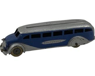 1122 - Antique Metal Greyhound Bus 2"x6"x1.5" (Description): Antique metal Greyhound bus toy featuring a classic streamlined Art Deco design in blue and silver paint. The die-cast model displays the Greyhound logo on the side and has white rubber wheels. Shows wear consistent with age and use. Measures 2 inches high by 6 inches long by 1.5 inches wide.