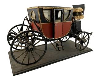 10 - Vtg Wood Carriage Model on Stand 10"x15.5"x7" (Description): Vintage wood carriage model displayed on a rectangular wooden stand. This detailed miniature depicts a 19th century style coach featuring a black and burgundy painted body with gold trim accents, glass or clear panel windows, a fringed driver's seat canopy, functional-looking doors, and four spoked wheels. The carriage includes fine details such as a folding step mechanism and hitching apparatus. Measures 10" x 15.5" x 7".
