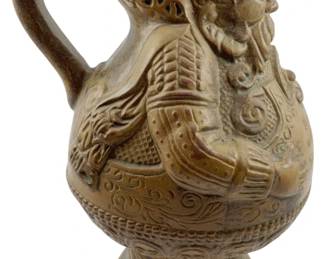 92 - Vtg German Stoneware Figural Pitcher 9"x6"x6" (Description): Vintage German stoneware figural pitcher featuring a bearded man in traditional Germanic attire. The vessel has a bulbous body with ornate relief decoration and German text reading "Reiner Wein und gutes Bier Sind des Wirtes schonste Zier" (Pure wine and good beer are the innkeeper's finest adornment). The piece displays a warm tan salt-glazed finish typical of German stoneware. Measures 9" x 6" x 6".