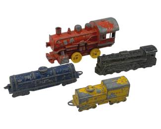 873 - 4pc Lot Vtg Metal Toy Train Locomotives 5" (Description): A collection of four vintage metal toy trains measuring 5 inches. The lot includes a red steam locomotive with yellow wheels, a blue tank car or locomotive, a black steam locomotive, and a yellow diesel-style engine. All pieces show significant paint wear consistent with age and play use, displaying their cast metal construction beneath the original painted finishes.