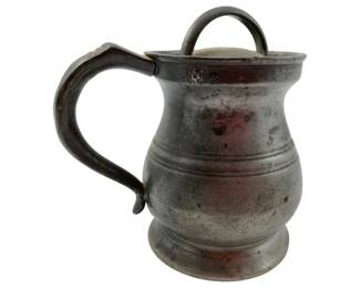 133 - Ant. Pewter Tankard w/ Lid & Handle Marked (Description): Antique pewter tankard featuring a hinged lid with loop handle and a curved side handle. The piece displays a baluster-form body with incised banding and sits on a footed base. Marked near the rim, likely indicating maker or verification marks. The pewter shows an aged patina consistent with its age. Measures 4"x4"x3".
