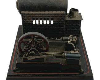 880 - Antique Tin Litho Steam Buggy 4"x8.5"x10" (Description): Antique tin lithograph steam engine toy featuring a black painted base with red pinstriping detail. The model includes a horizontal boiler mounted above a brick-pattern facade, a working flywheel with red painted spokes, cylinder, piston assembly, and connecting rods. A small smokestack rises from the brick structure. This educational toy demonstrates the mechanics of steam-powered machinery.
