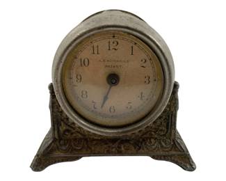 778 - A.E. Hotchkiss USA Clock 2.5"x3"x1.5" (Description): A.E. Hotchkiss USA patent clock featuring an ornate decorative base with embossed scrollwork design. The clock has a round face with Arabic numerals. Measures 2 1/2 inches by 3 inches by 1.5 inches. Used as is electric/electronic/mechanical item. No guarantee all components, untested.