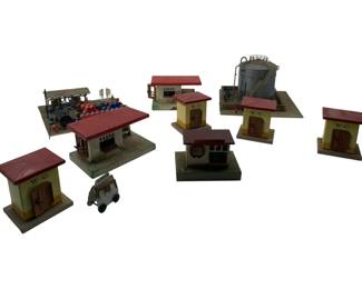 330 - Kibri Train Display Set 4"x6"x6" (Description): Kibri train display set featuring a collection of miniature buildings and accessories for model railroad layouts. The set includes multiple painted wooden structures with characteristic red roofs, including W.C. outhouses, a station building, a fuelor water tank on a platform base, and various other trackside buildings. A small vehicle figure is also included. The pieces display vintage charm typical of mid-century