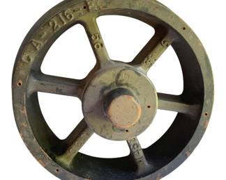 762 - Wooden Train Wheel 19"x8" (Description): Wooden train wheel featuring a five-spoke design with a central hub. The wheel shows cast alphanumeric markings on the outer rim. Measures 19 inches in diameter by 8 inches deep.
