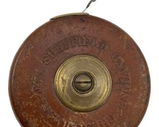 734 - Sheffield Brass & Leather Measuring Tape (Description): Sheffield antique brass and leather measuring tape. This classic tool features a brass center mechanism housed in a leather case. Measures 1" x 3".