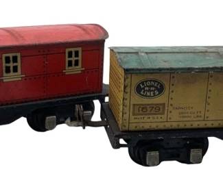 265 - Lionel Train Cars 3"x3"x8" (Description): Lionel train cars featuring a red caboose numbered 1682 and a boxcar numbered 1679. Each car measures 3 inches by 3 inches by 8 inches.