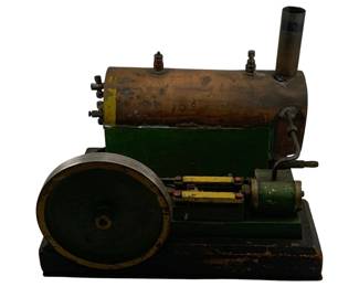 933 - Antique Steam Engine 8"x13"x12" (Description): Antique steam engine featuring a copper boiler mounted on a green and black painted metal base. The engine includes a large flywheel, twin cylinder mechanism with yellow accents, and a tall smokestack. The piece shows authentic age-related patina throughout. Measures 8" x 13" x 12".